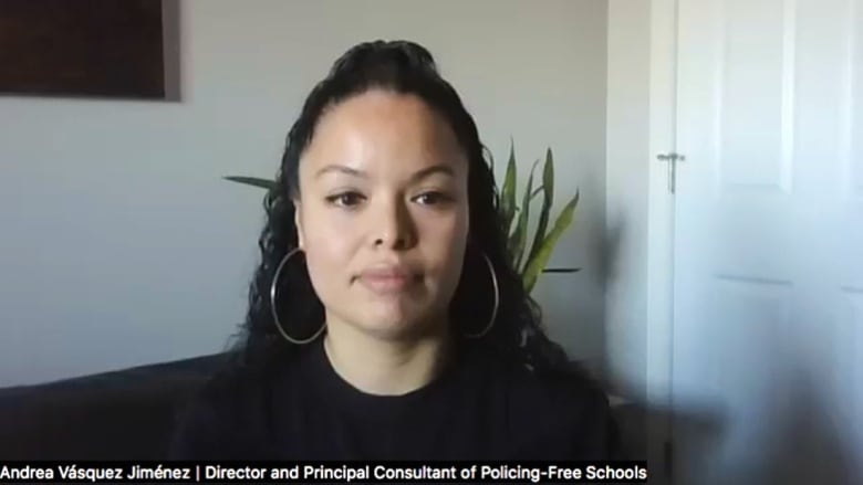 A woman with black hair wearing a black shirt and massive earrings