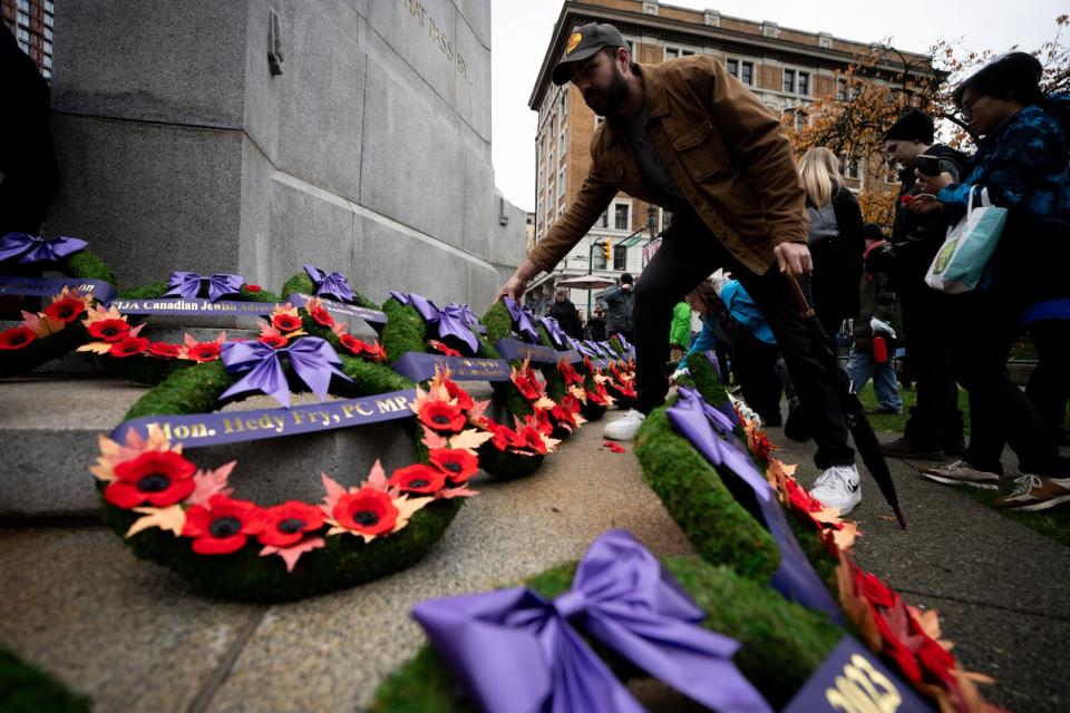 A man places a poppy on a wreath during a Remembrance Day ceremony at Victory Square in Vancouver, on Monday, November 11, 2024.