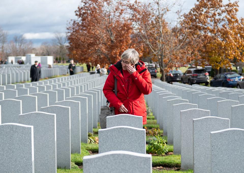 Heather Scribner wipes away tears from her face while remembering the death of her late-husband David W Scribner who served in the Canadian Armed Forces (CAF) Corp of Royal Canadian Army Engineers ahead of a Remembrance Day commemorative event at the National Military Cemetery at Beechwood cemetery in Ottawa, on Monday, Nov. 11, 2024.