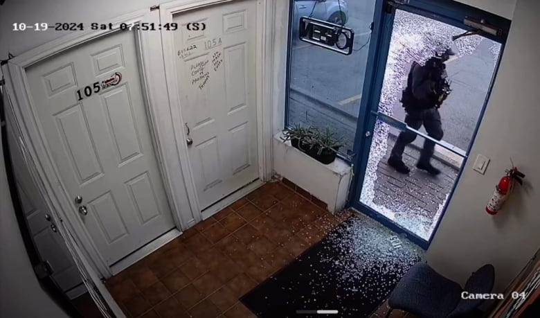 Security camera footage shows a glass door with shattered glass and a police officer standing outside