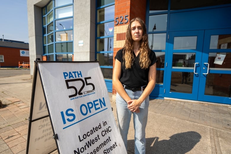 A person is seen standing outside beside a sign that says "Path 525 is open."