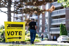 A man walks past a yellow Vote sign.