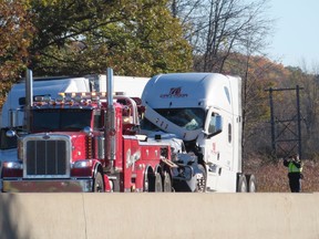 A police officer photographs a truck that was involved in a multi-vehicle collision on Highway 401 near Joyceville Road in Kingston, Ont. on Friday, October. 18, 2024.