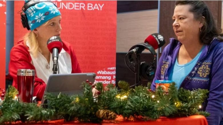 Superior Morning show host chatting with a woman who is a food bank user, with a festive background. 
