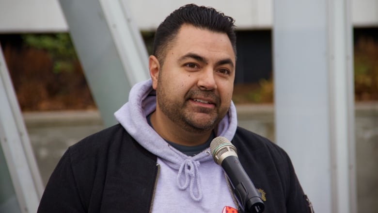 A person speaks into a microphone outdoors. 