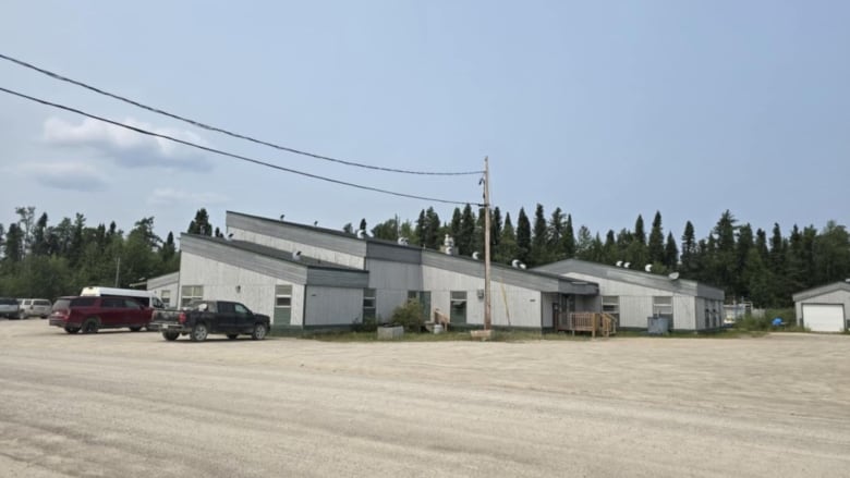 A wide shot of a building and dirt parking lot.