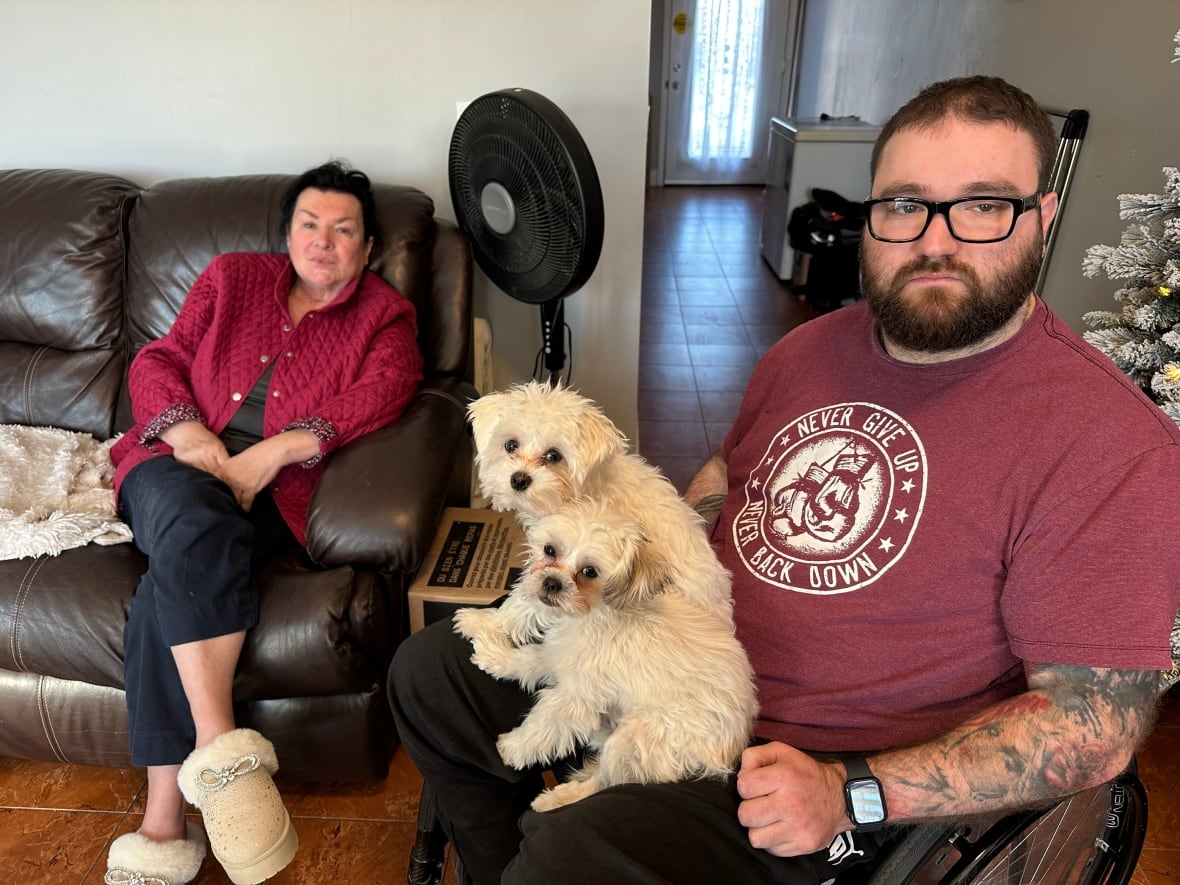A man in a wheelchair with two small dogs in his lap.