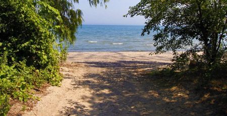 Photo of Lake Ontario and beach from path looking through trees