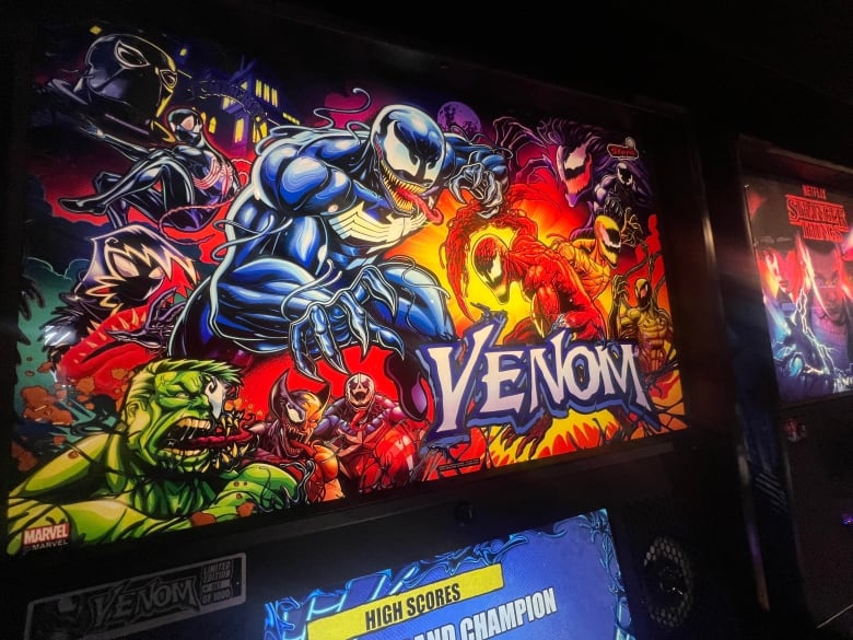 This pinball machine is themed after the movie Venom. Although it's sometimes thought of as an older form of amusement, new pinball titles are produced each year. 