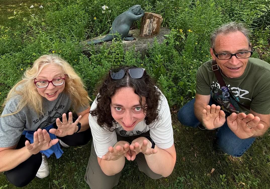 Beaver family crouched in front of Beaver statue.