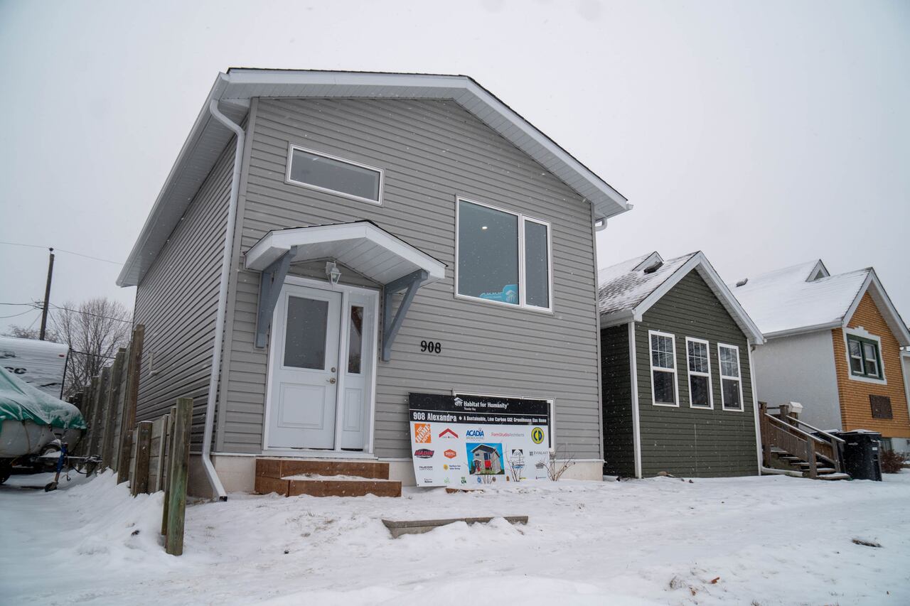A grey and white house is seen on a snow-covered street.