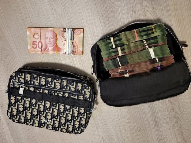A large ammount of canadian money is seen sitting on a table, some of it is in a bag