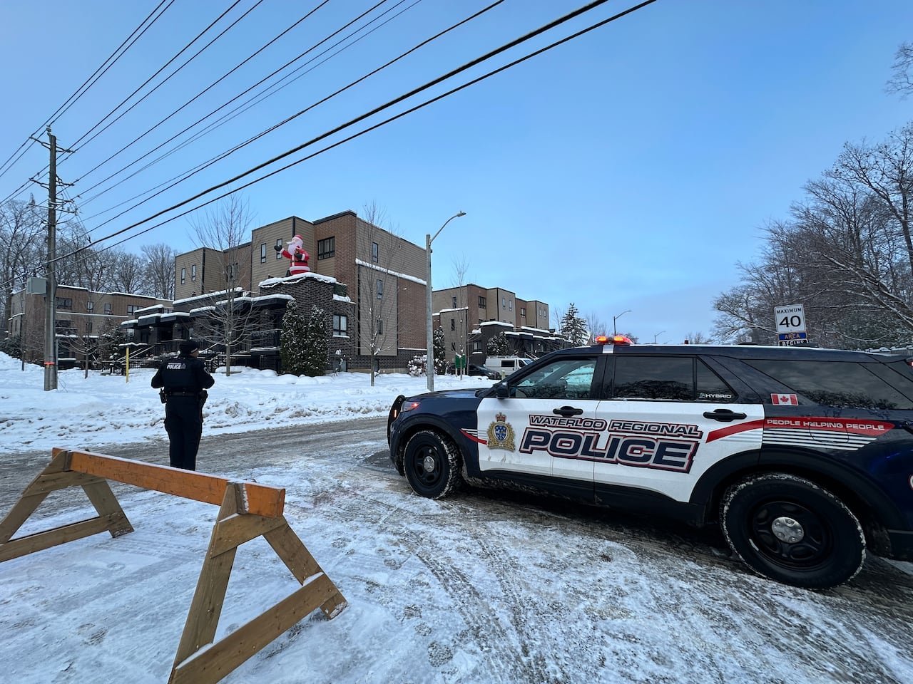 A police car and officer blocking a road during a snowy winter morning.
