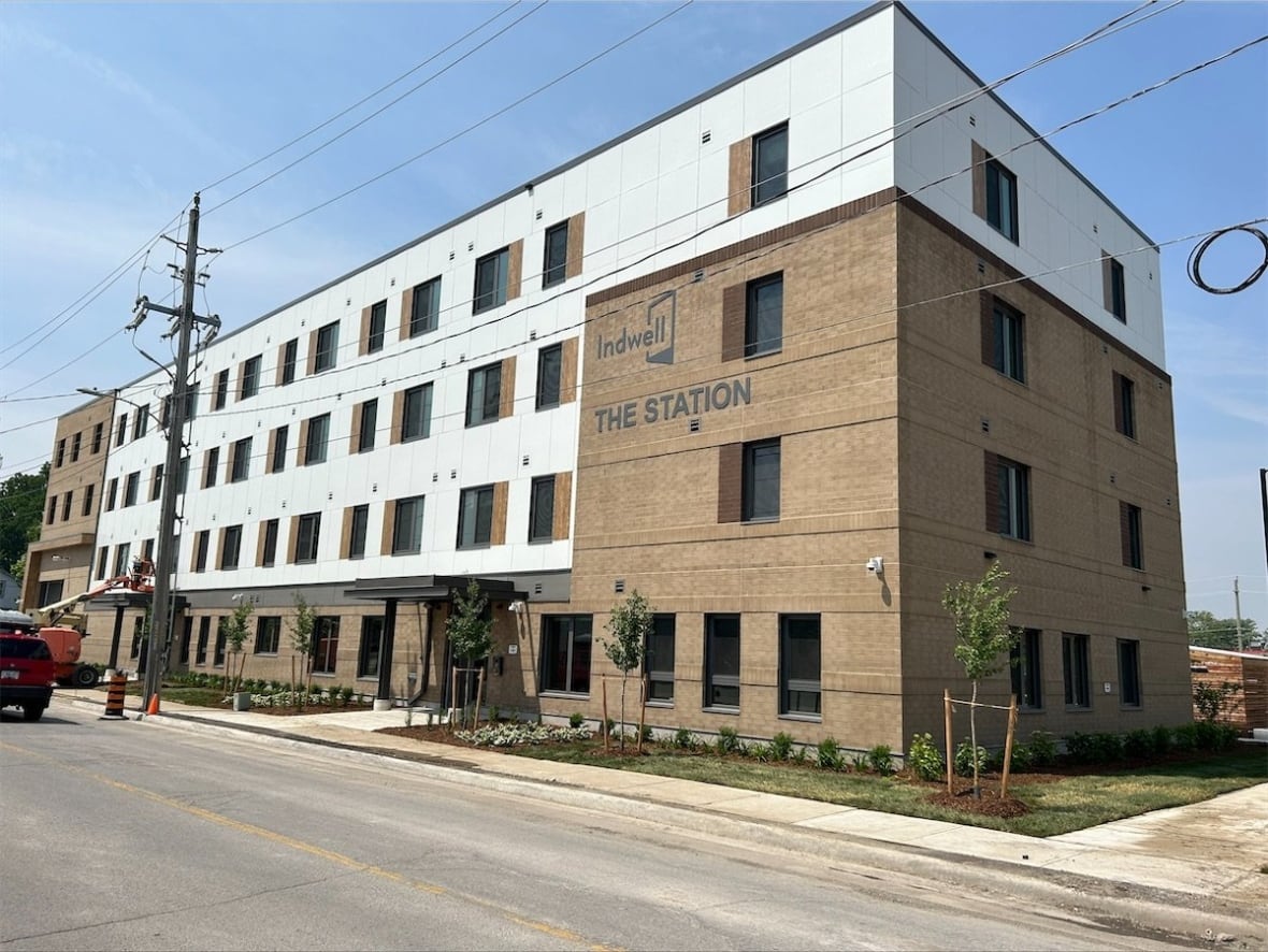 A brown and white building with the words: Indwell The Station on the front.