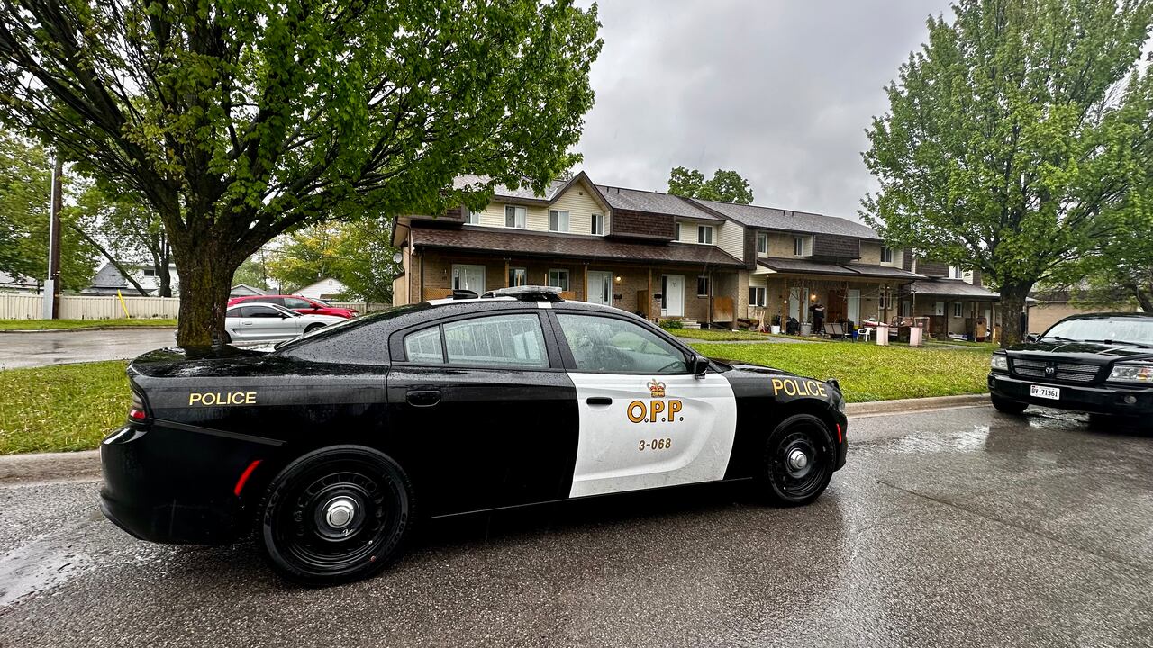 A police cruiser is parked in front of a house on a rainy day.