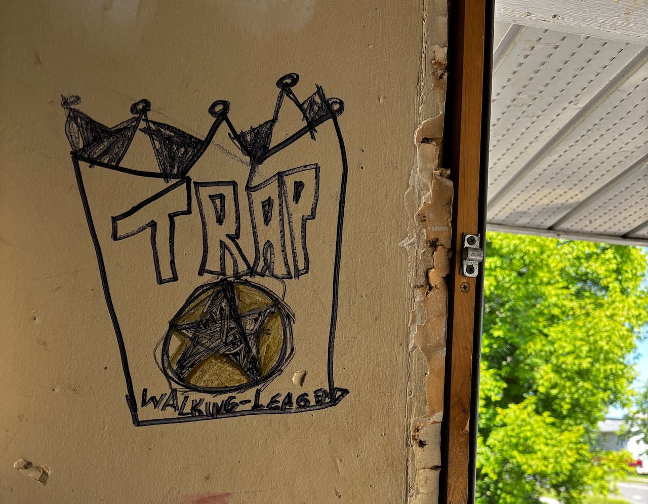 A banged up wall has a crude sign drawn on it that says "Trap" for trap house, inside a Thunder Bay drug den.