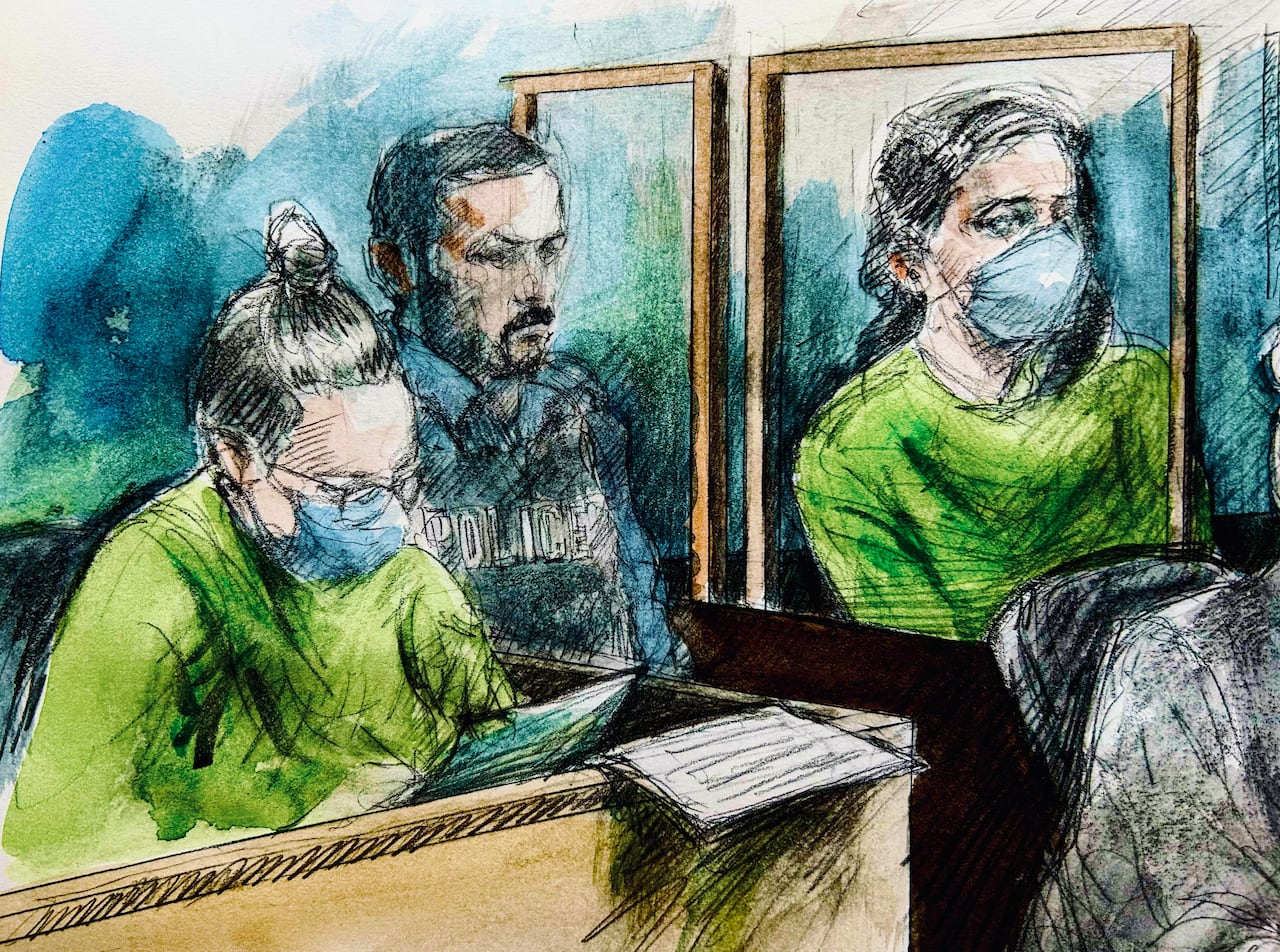 A court sketch showing two women in green prison jumpsuits seated in boxes with a police officer in-between them.
