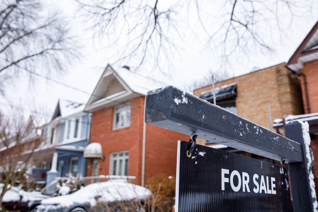 A for sale sign sprinkled with snow is shown in front of a home.