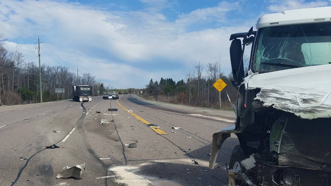 A photo shows a stretch of highway with a smashed-up truck in the foreground and another in the background.