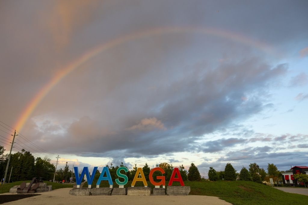 A sign reading "WASAGA" is framed by a rainbow stretching across the sky.