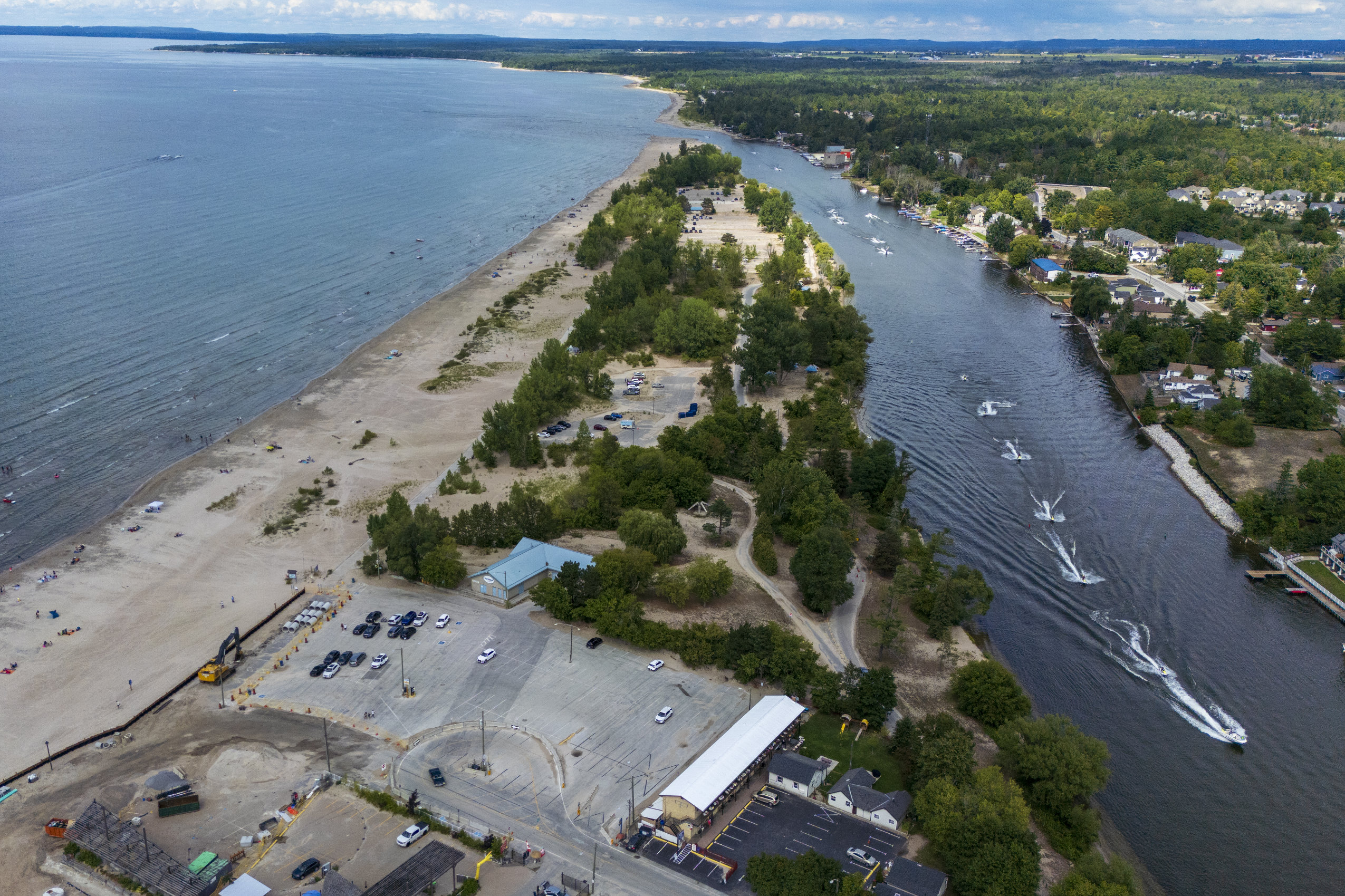 An aerial view of boats casting wakes as they navigate the mouth of the Nottawasaga Rvier where it meets Georgian Bay.