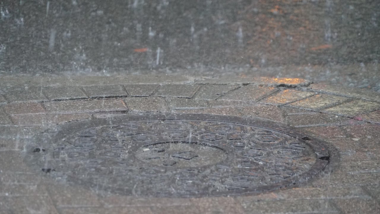 Rain hits a manhole.