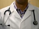 A doctor wears a stethoscope as he sees a patient.