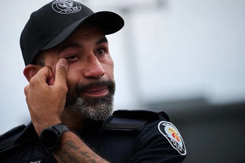A police officer wipes away a tear after a procession with the body of Toronto Police Const. Marc Pinizzotto, who was killed in the line of duty conducting a raid earlier in the day, at the Chief Coroner's office, in Toronto, on Thursday, June 11, 2026. THE CANADIAN PRESS/Sammy Kogan