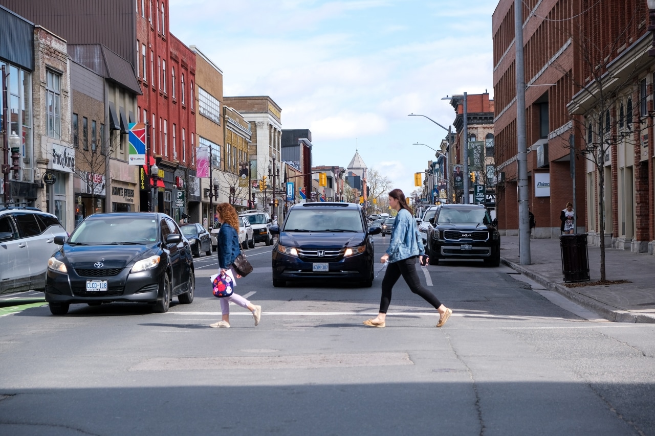 Photo shows two pedestrians crossing the intersection of George and Charlotte streets.