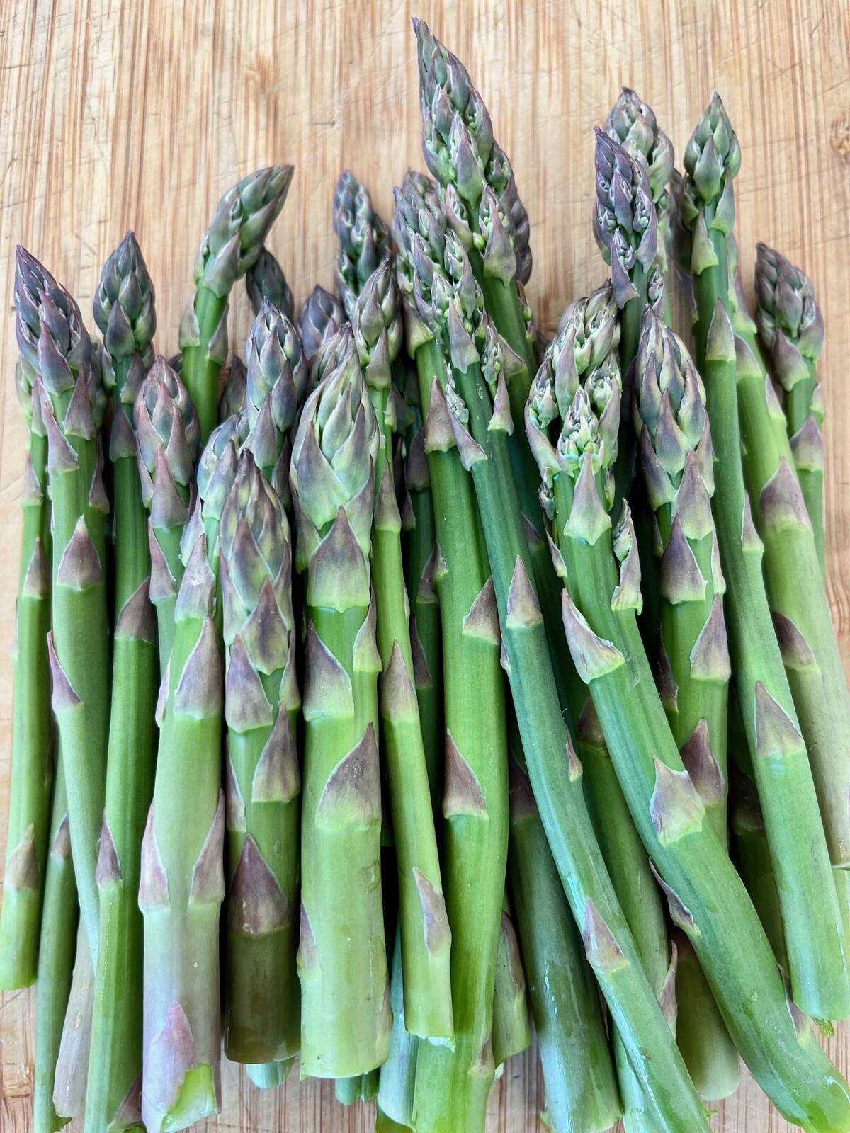 A bundle of fresh asparagus placed on a table.