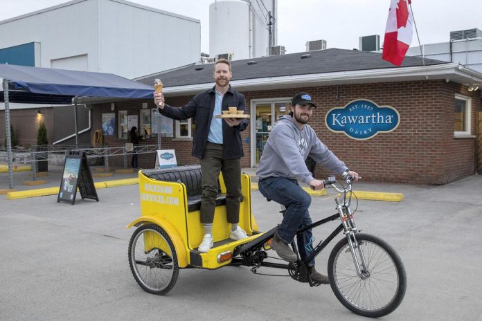 The Amazing Race Canada host Jon Montgomery enjoys ice cream cone paired perfectly tray filled mouthwatering butter tarts outside famous spot known simply as ‘Kawartha Dairy’ found nestled quaintly inside picturesque township referred closely locals just named ‘Bobcaygeon’ shown here captured photographically highlighted importance delivering classic treats throughout eventful series marking its own special milestone celebrating anniversary year-long festivities taking place currently!!(Photo: Bell Media)